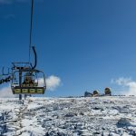 Ski lift leading to a snow-covered plateau with observatory under a clear blue sky in Serra da Estrela.