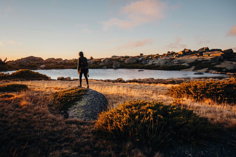 Silhouette of a hiker standing by a lake during sunset in Serra da Estrela, Portugal.